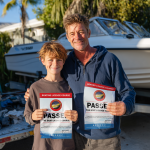 ALL - father and son in front of boat on trailer holding certificate